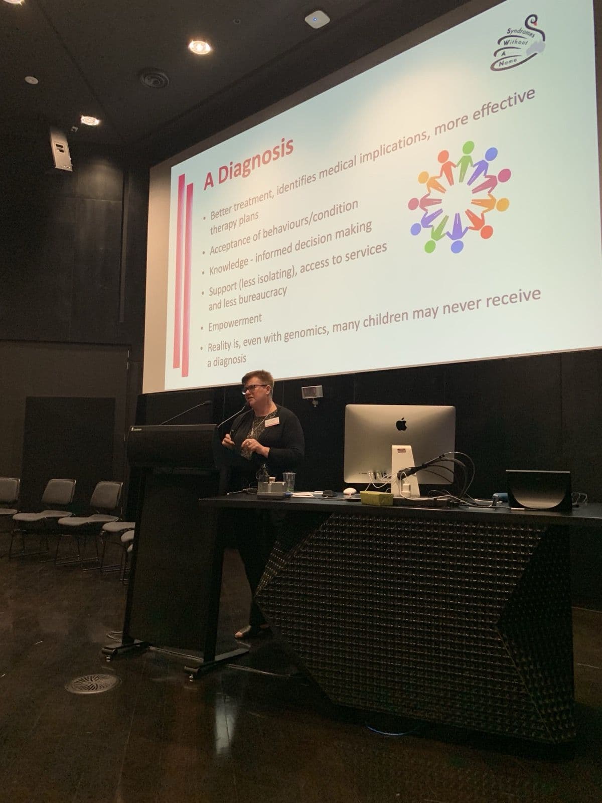Heather Renton presenting in front of a slide titled “A Diagnosis”