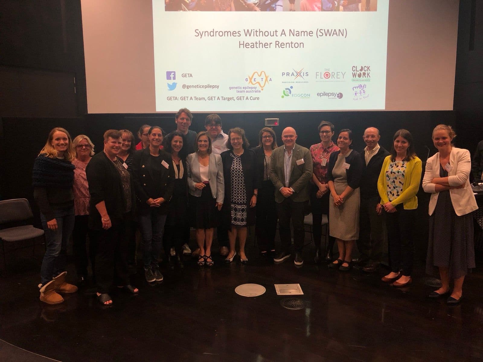 Speakers and organisers standing together in front of the stage